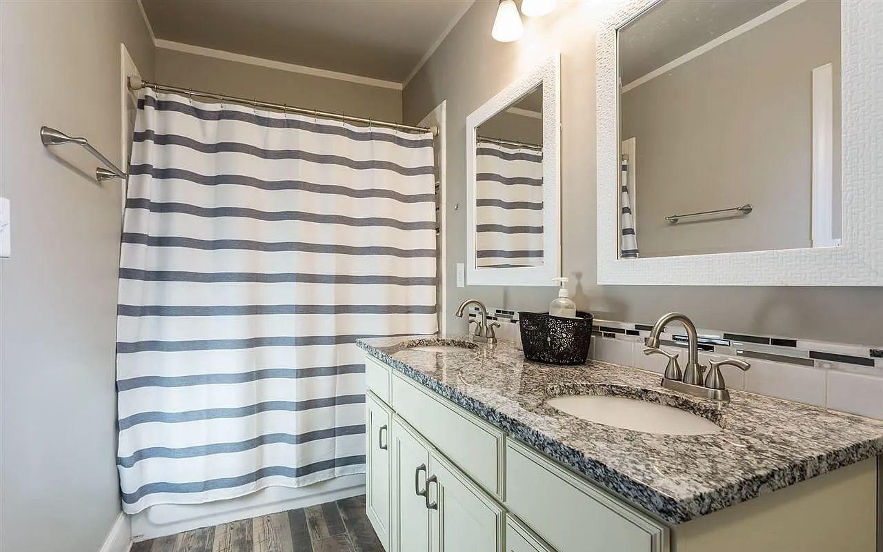 Renovated bathroom with a tiled shower surround, vanity and framed mirror