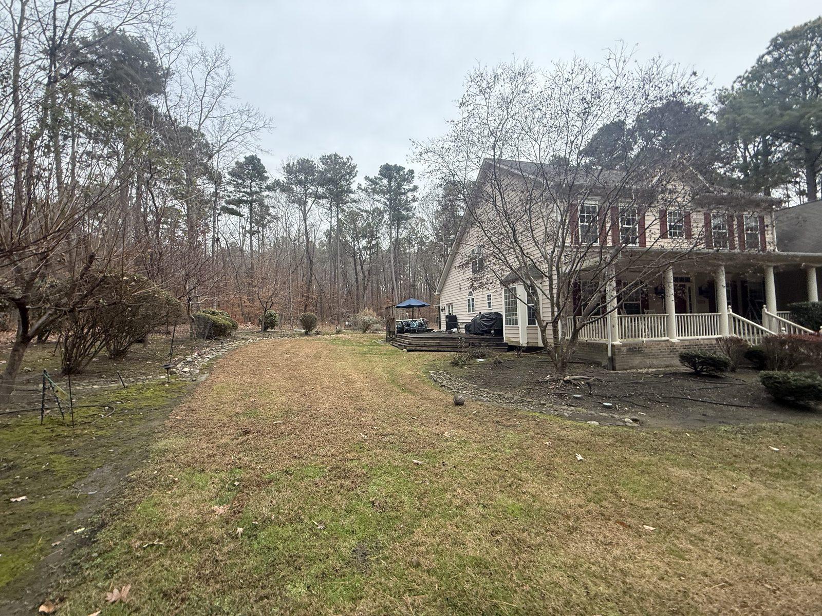 The rear of the house before work began, with a timber deck and screened porch above a sloping lawn