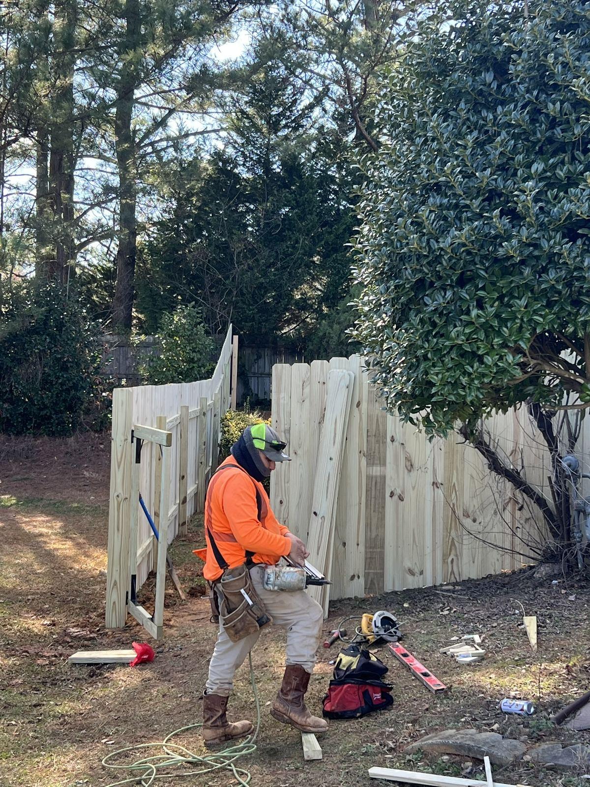 Carpenter setting posts and building fence panels on site