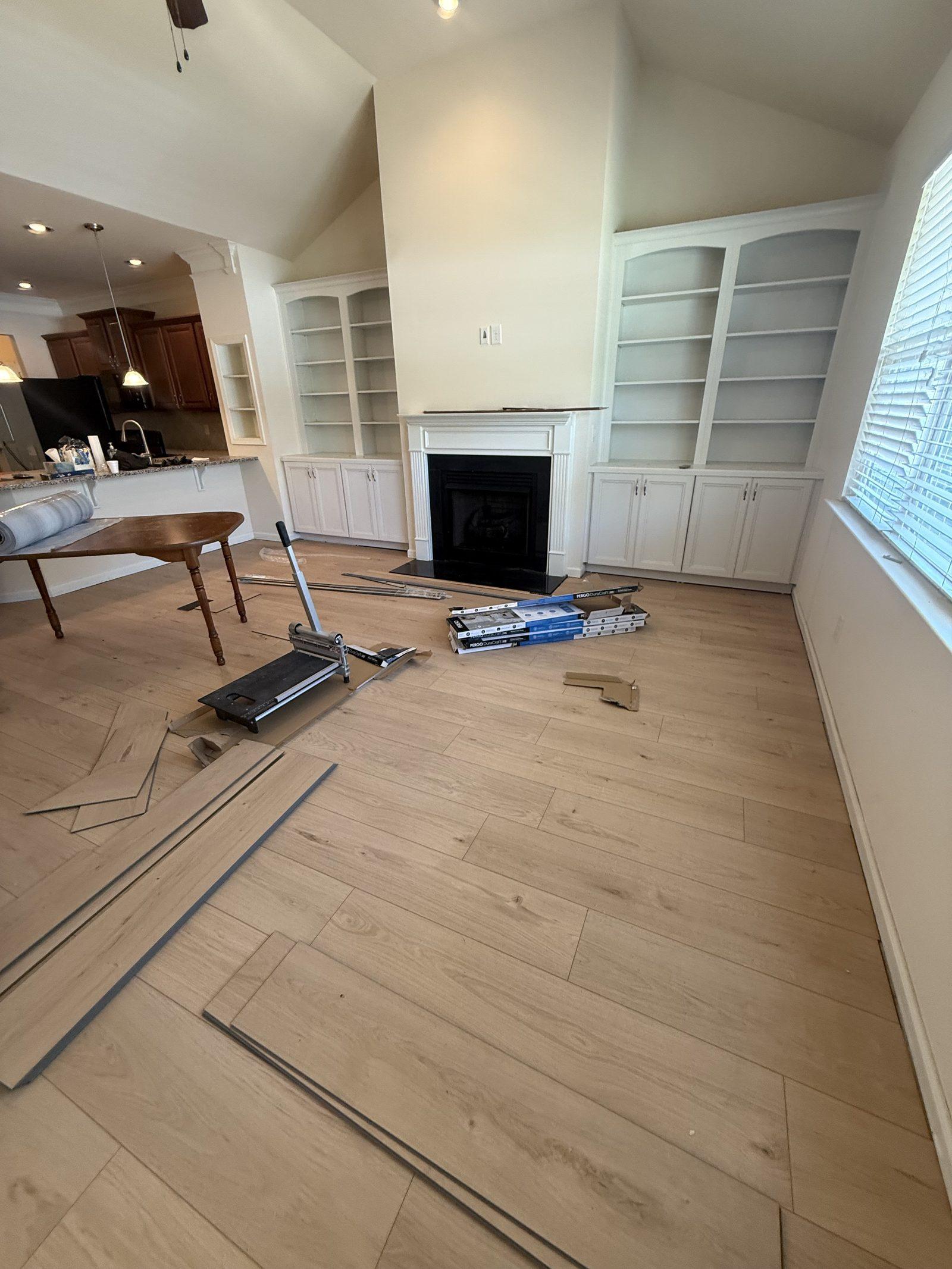 New plank flooring part-laid across the room with loose boards and pull bars still on the floor