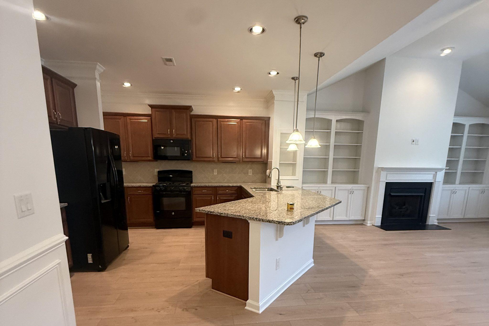 The kitchen and great room after the new light wide-plank floor was laid through both spaces