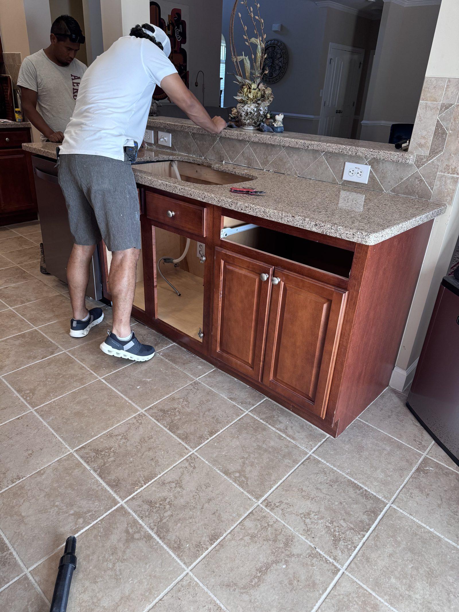 A carpenter fitting the countertop back down onto the rebuilt island base