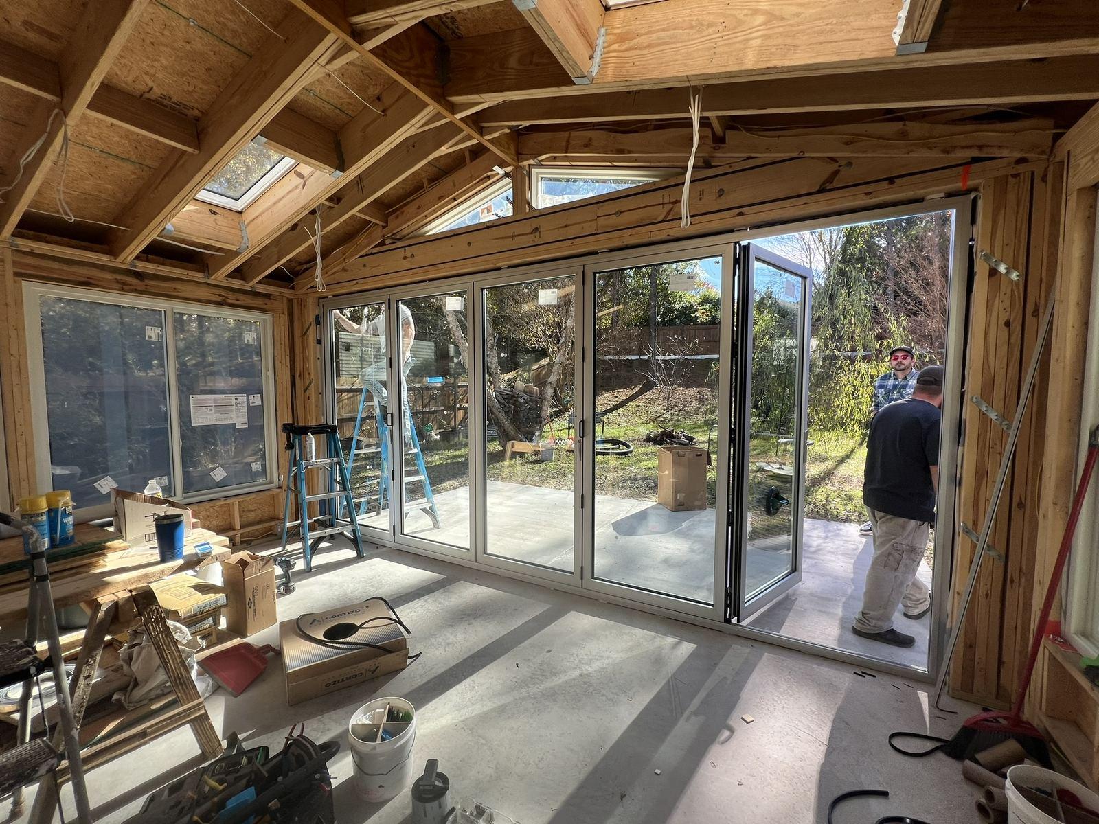 Sunroom addition mid-construction with exposed vaulted framing, skylights and installed glazing — Miroslav Sunroom