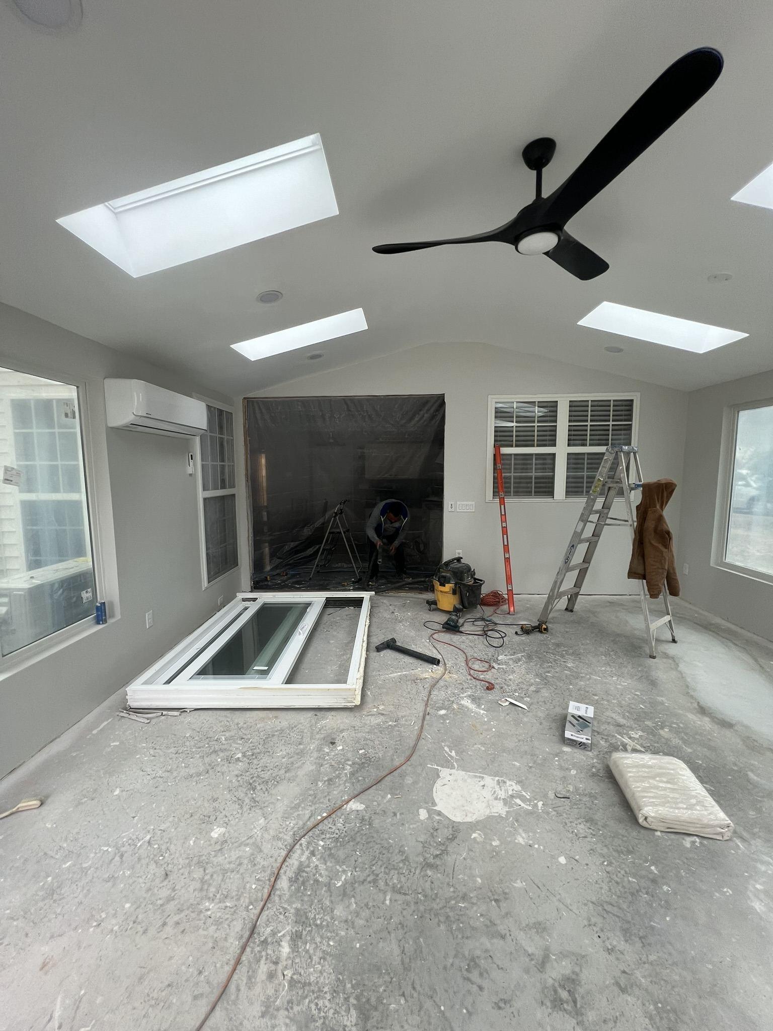 Sunroom interior during late-stage construction with the vaulted ceiling, skylights and heat pump installed, a glazed unit yet to be set and the slab not yet finished
