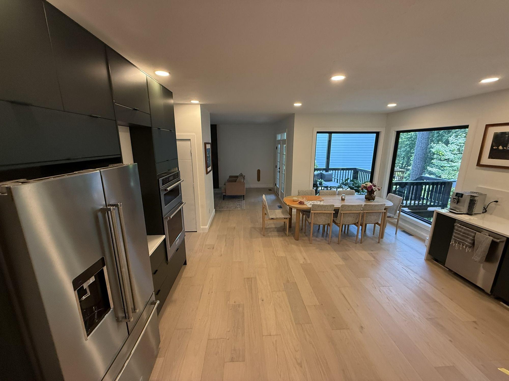Completed kitchen with island, integrated appliances and dark cabinetry opening onto the dining area — Olga Kitchen Addition