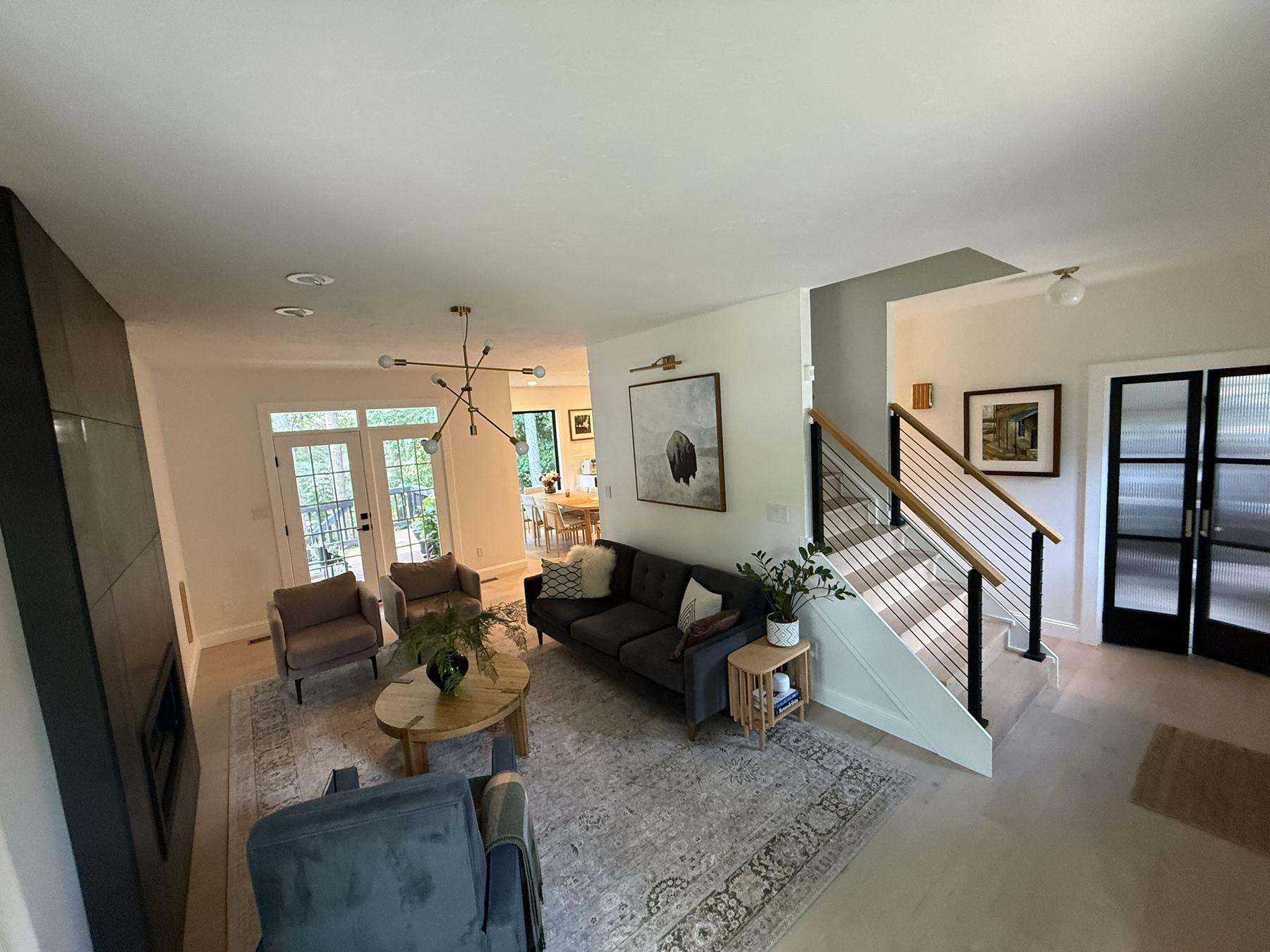 Completed living area with open staircase, cable railing and black-framed doors — Olga Kitchen Addition