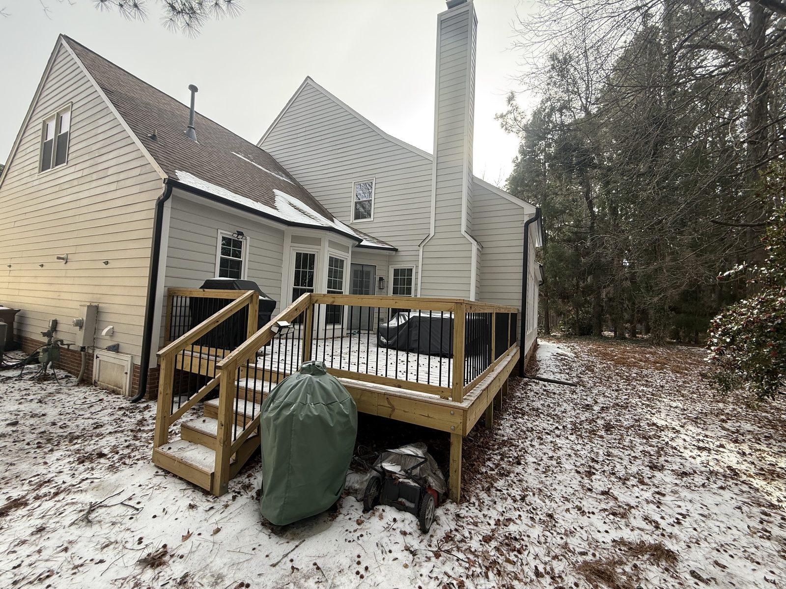 The raised rear deck before work, open to the sky with its metal balusters and stair run in place