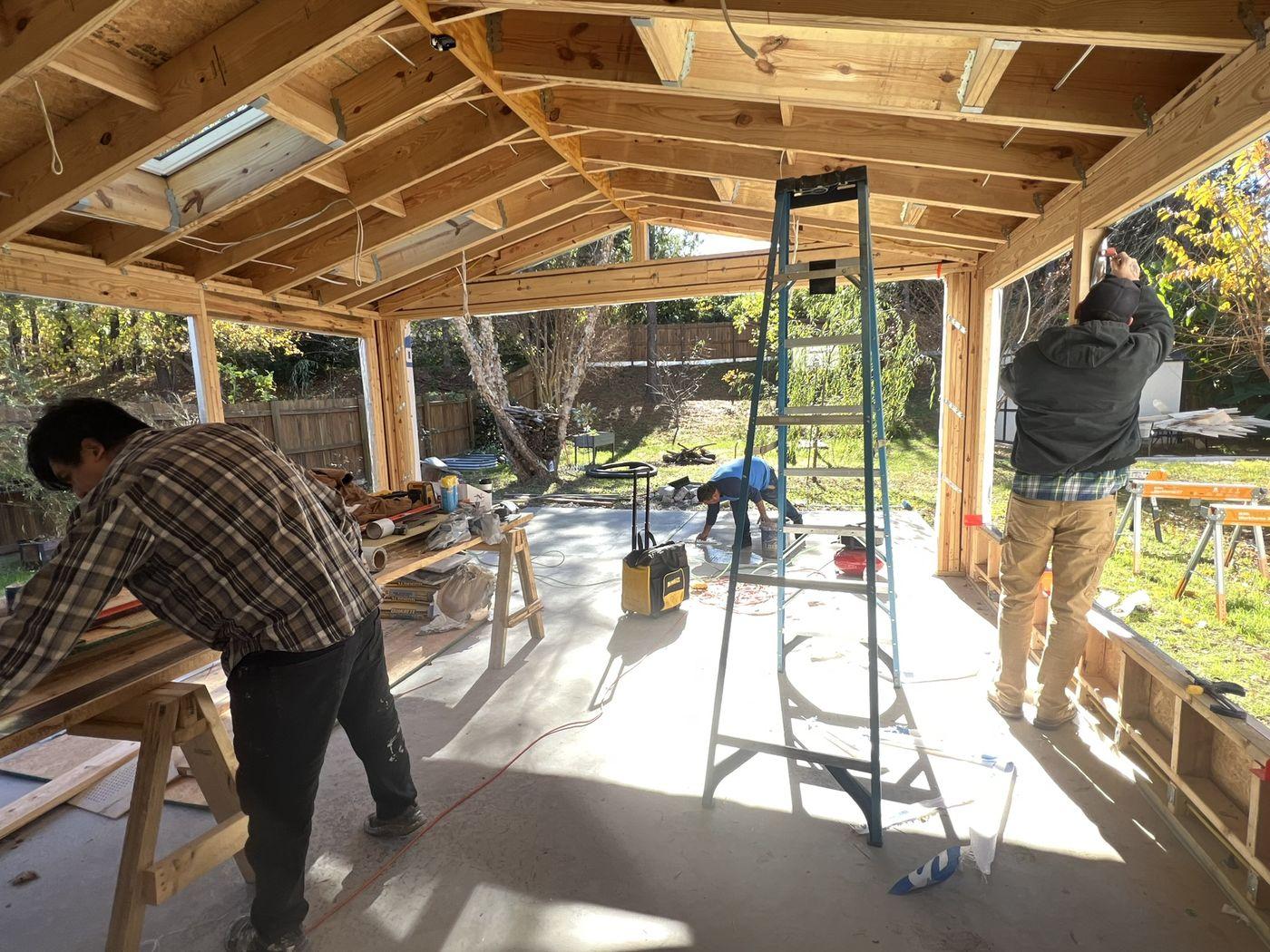 Carpenters working inside a framed sunroom addition during construction