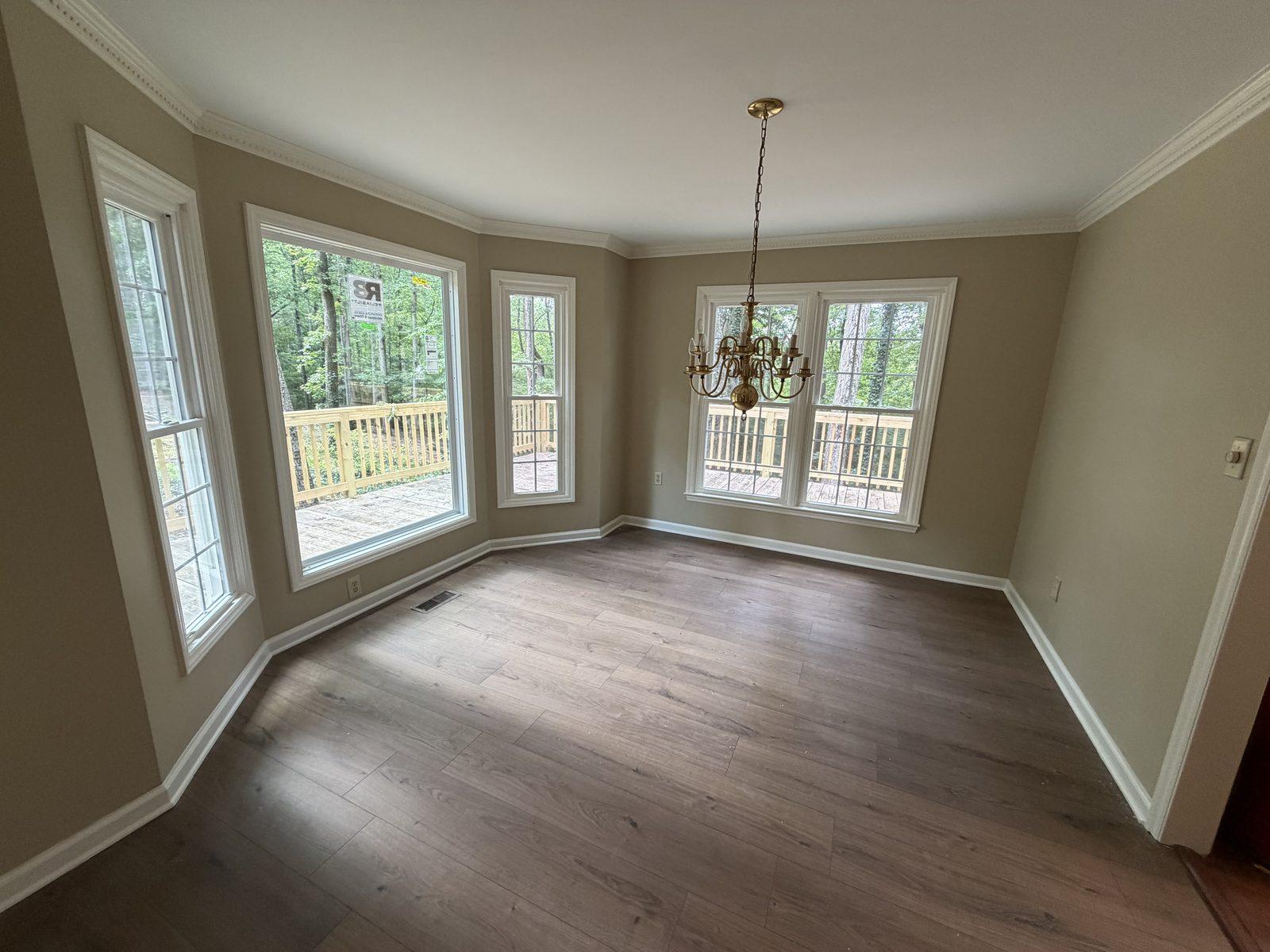 The same dining room rebuilt, with new windows in the bay, a smooth ceiling, new crown molding and plank flooring