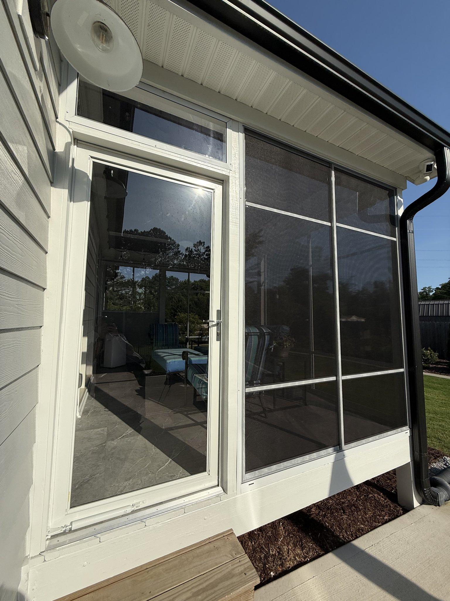 Detail of the room's sliding screened panels and door, set in white frames against the siding