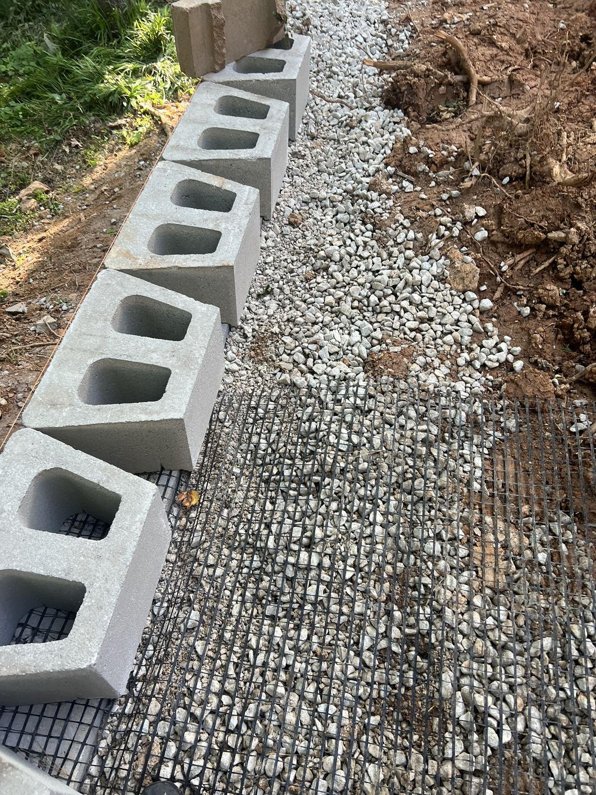 Drainage stone and geogrid laid behind the first course of block at the wall base