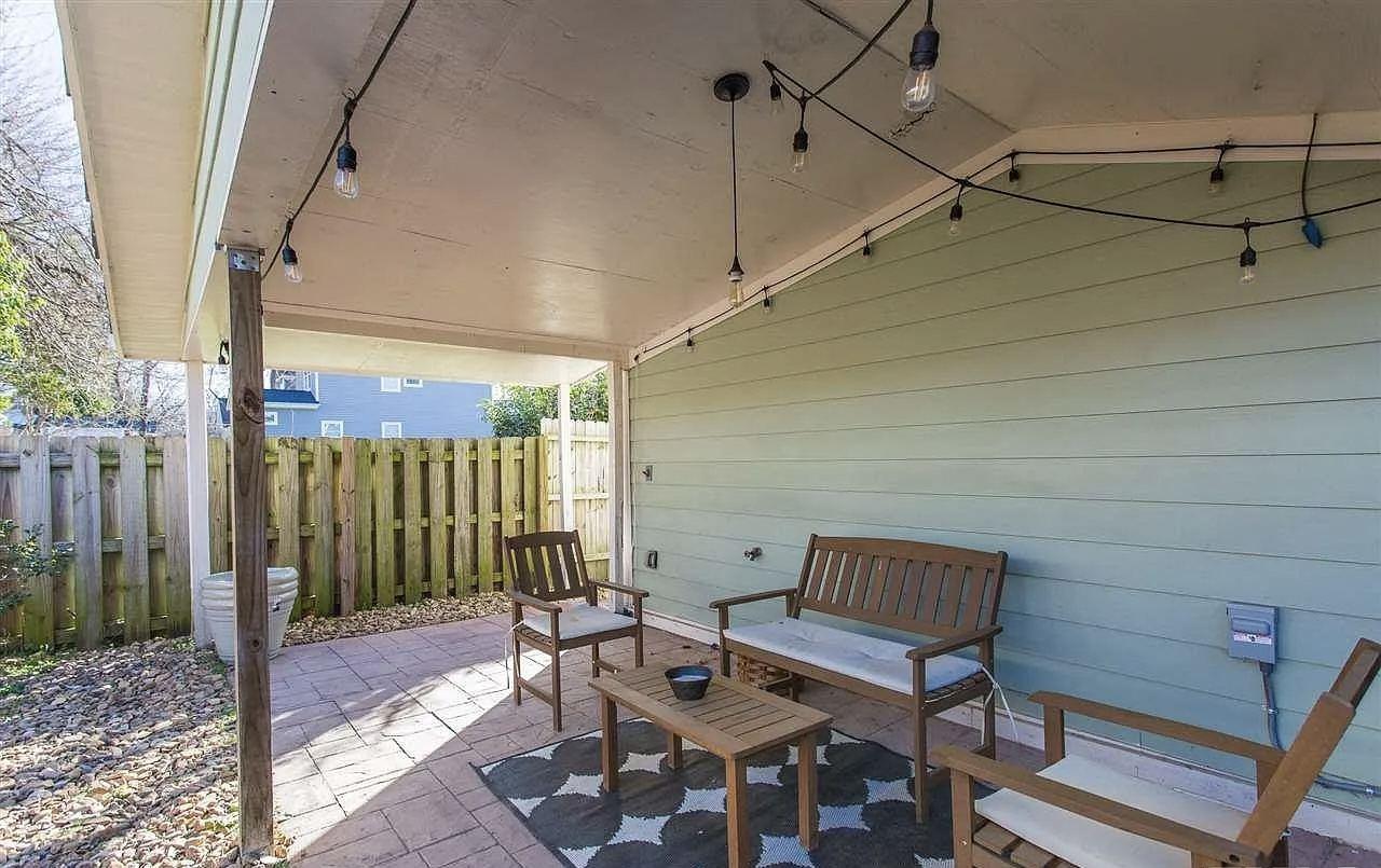 Covered outdoor seating area with string lighting at the rear of the renovated house