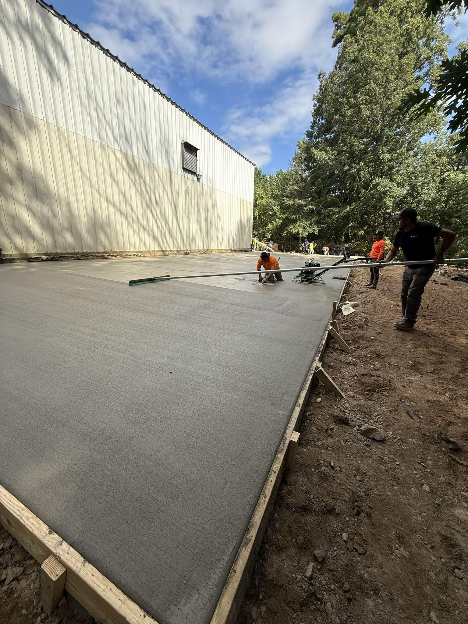 Crew working a freshly placed concrete slab running the length of a commercial building
