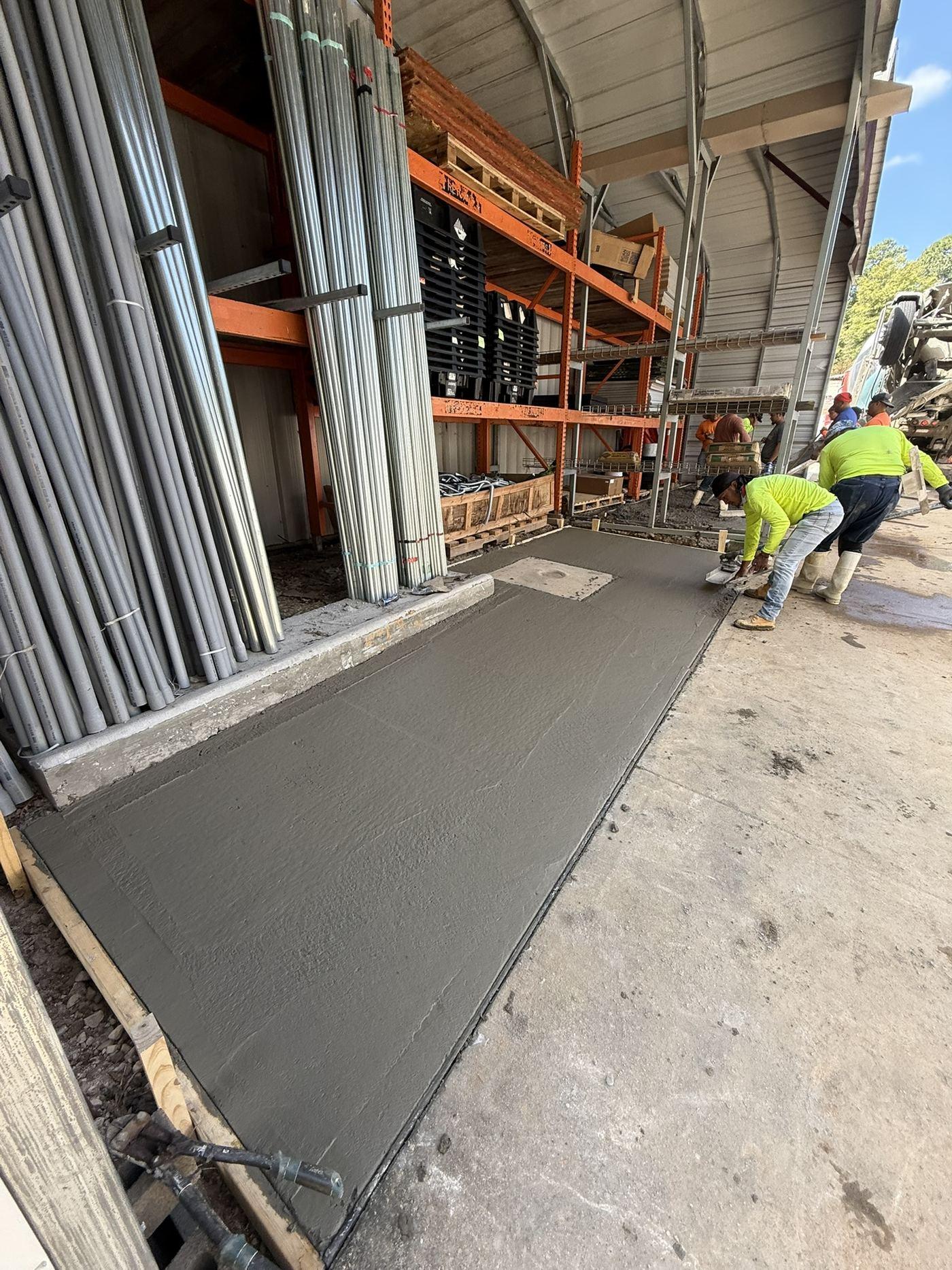 Interior warehouse floor slab being finished with storage racking in the background