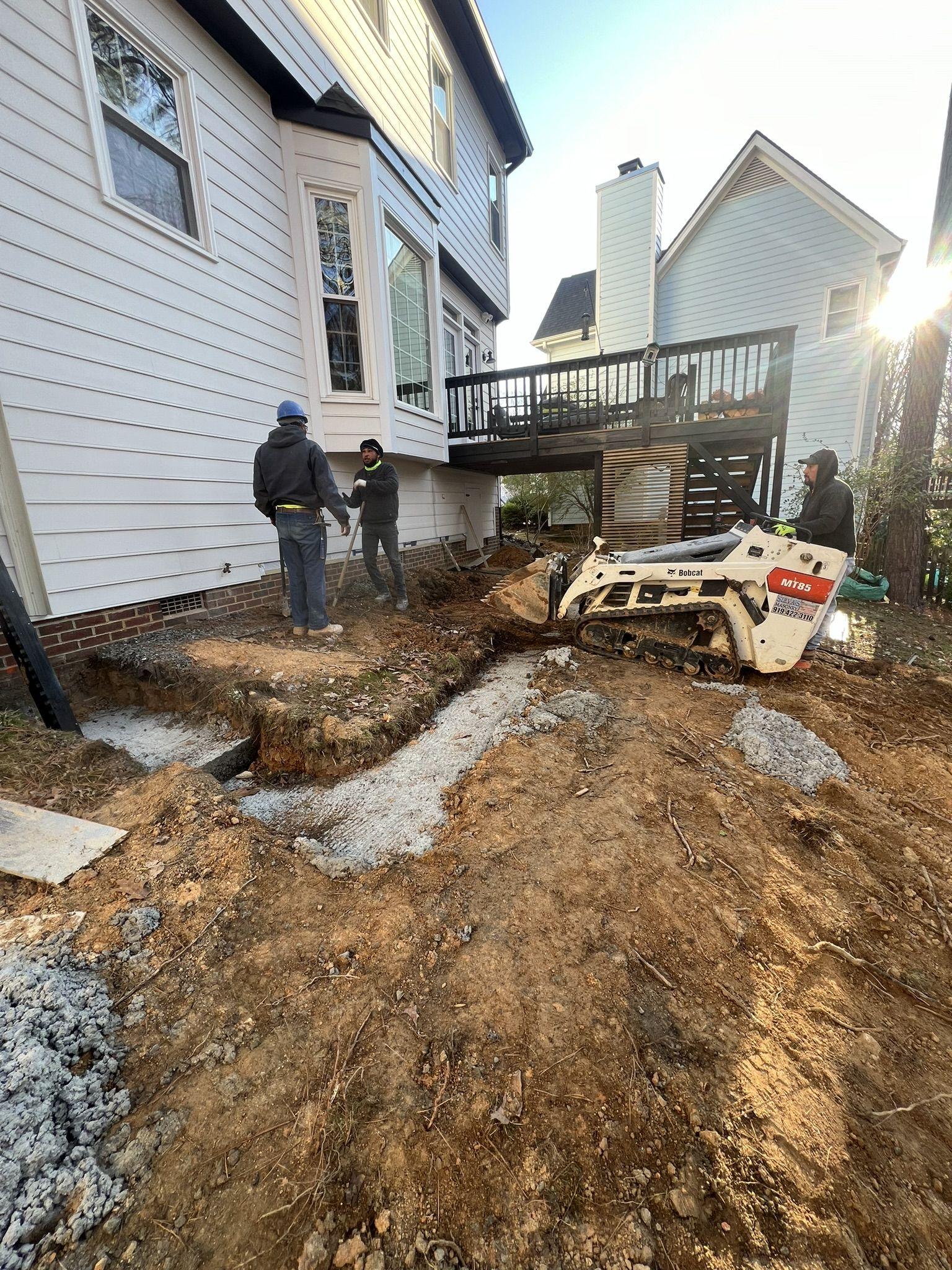 Excavation for addition footings with a compact track loader working beside the house