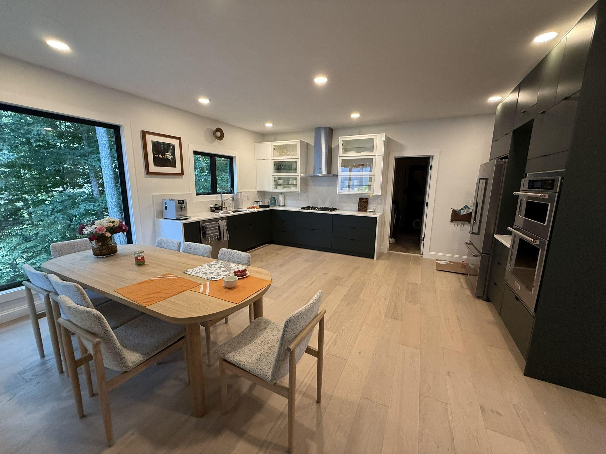 Finished kitchen and dining addition with dark cabinetry, oak flooring and full-height windows