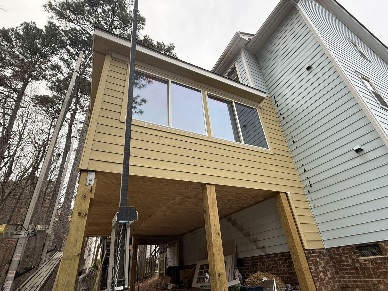 An elevated addition carried on new posts with cross-bracing, part-way through construction — Park Sunroom